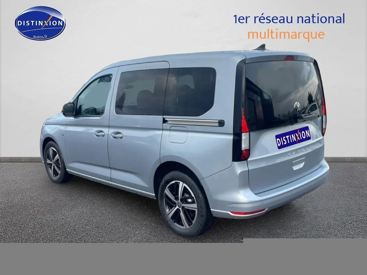 Volkswagen Caddy gris argent vu en 3/4 arrière droit, avec vitres teintées et jantes alliage noires.