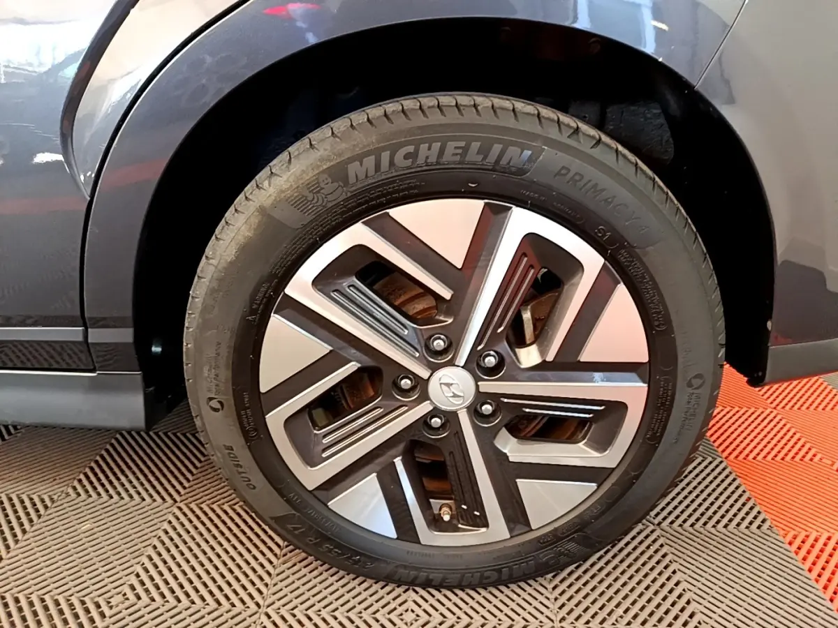 Gros plan sur la roue avant droite grise d'un Hyundai Kona électrique avec jante alliage bicolore et pneu Michelin.