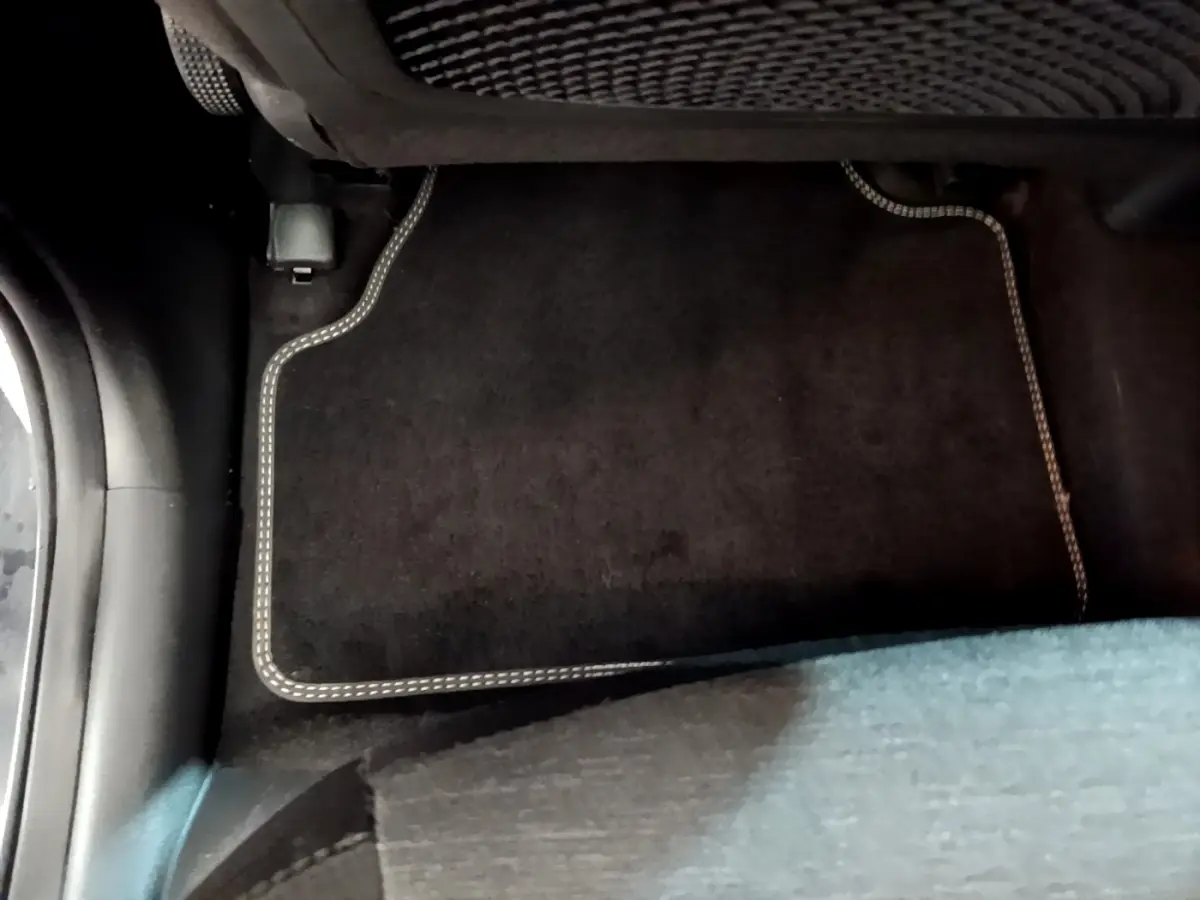 Vue intérieure du plancher arrière côté droit d'un Hyundai Kona électrique avec tapis de sol noir à surpiqûres claires.