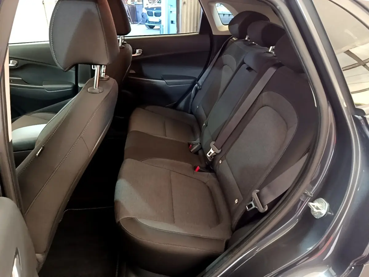 Vue intérieure côté droit sur la banquette arrière noire du Hyundai Kona électrique 2021 avec portes ouvertes.