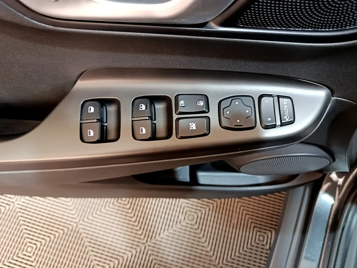 Vue rapprochée des commandes de lève-vitres et rétroviseurs sur la porte côté conducteur d’un Hyundai Kona électrique gris.