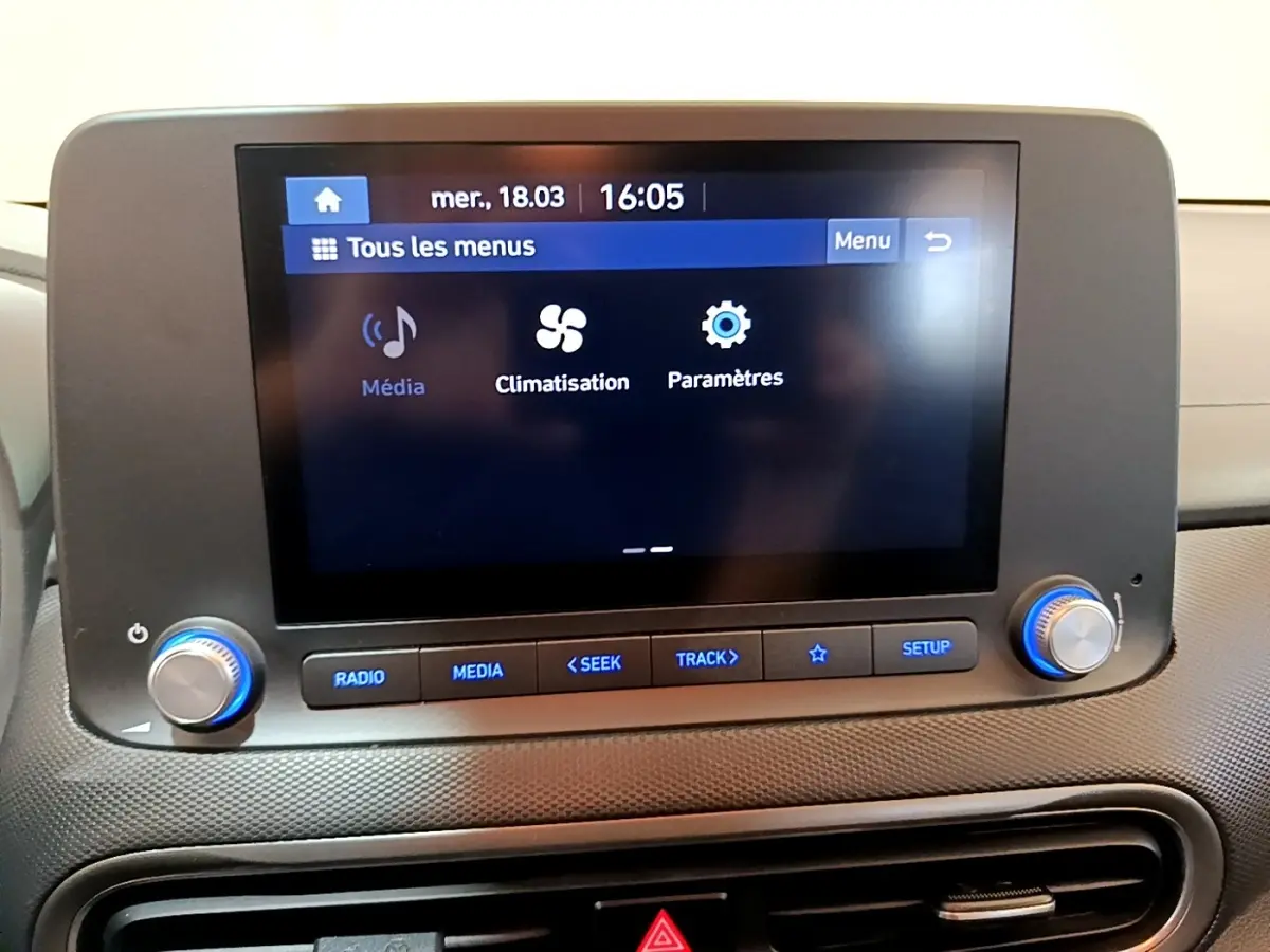 Écran tactile central affichant les menus média, climatisation et paramètres dans l’habitacle d’une Hyundai Kona électrique.