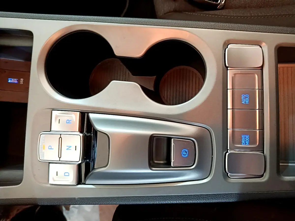 Vue rapprochée de la console centrale grise du Hyundai Kona électrique 2021 avec sélecteur de vitesses boutons et commandes éclairées.