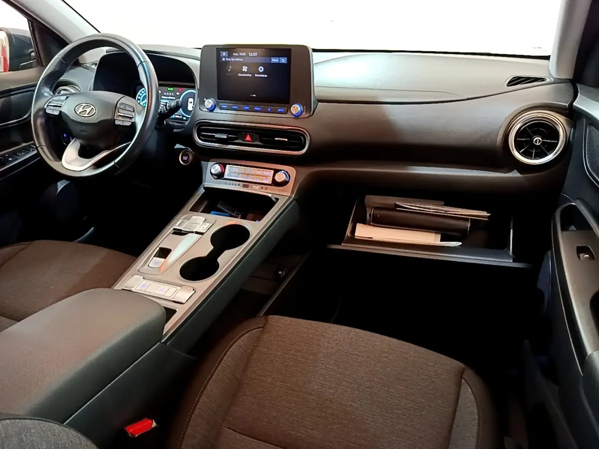 Intérieur noir et gris de la Hyundai KONA électrique 2021, vue de face côté conducteur avec tableau de bord et écran tactile.