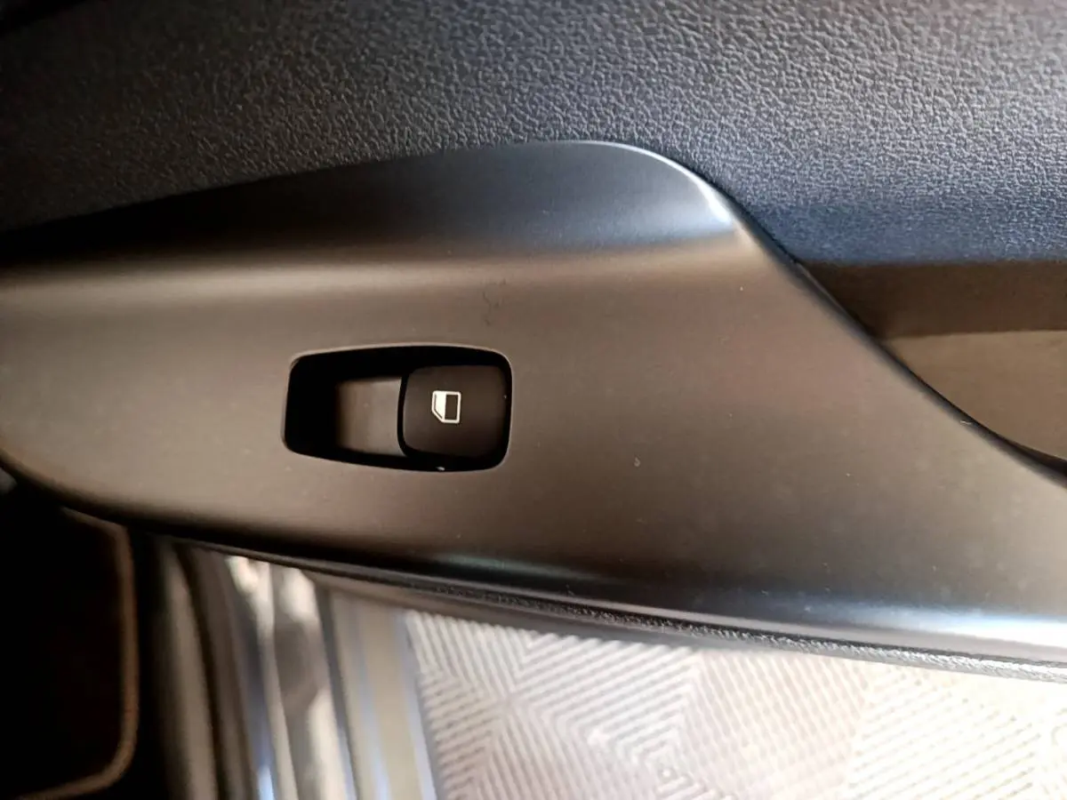 Gros plan sur le bouton de commande de lève-vitre côté conducteur d’un Hyundai Kona électrique 2021, intérieur noir.