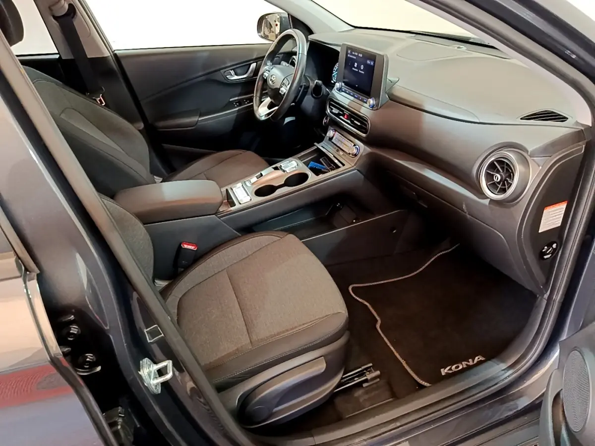 Vue intérieure côté conducteur du Hyundai Kona électrique 2021, sièges gris et tableau de bord avec écran tactile.