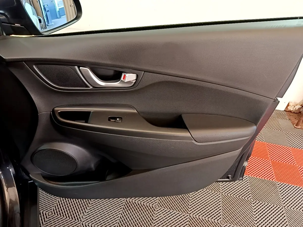 Vue intérieure côté gauche de la porte avant d'une Hyundai Kona électrique 2021, avec garniture noire et poignée argentée.