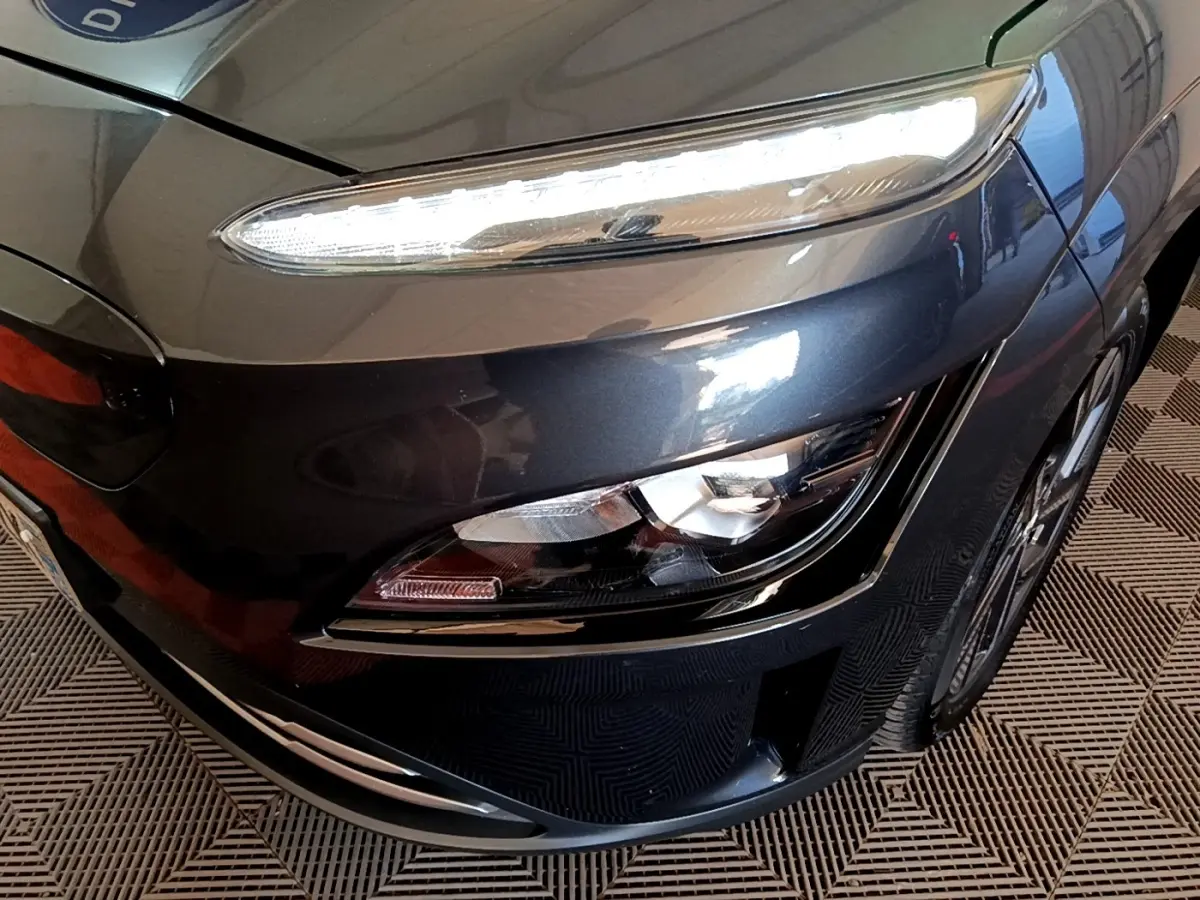 Gros plan sur l'avant droit gris foncé du Hyundai Kona électrique 2021, mettant en valeur ses phares LED distinctifs.