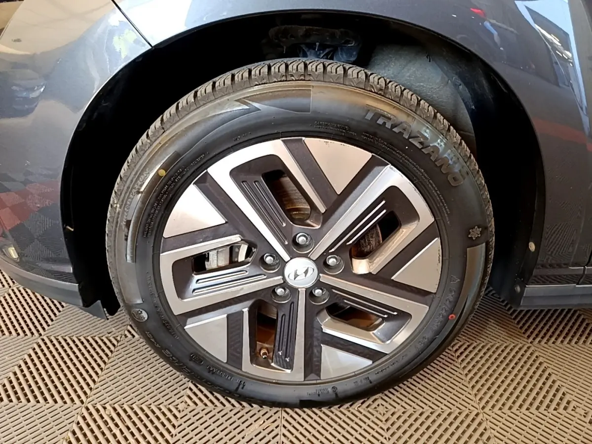 Gros plan sur la roue avant droite d'une Hyundai Kona électrique gris foncé avec jante alliage bicolore.