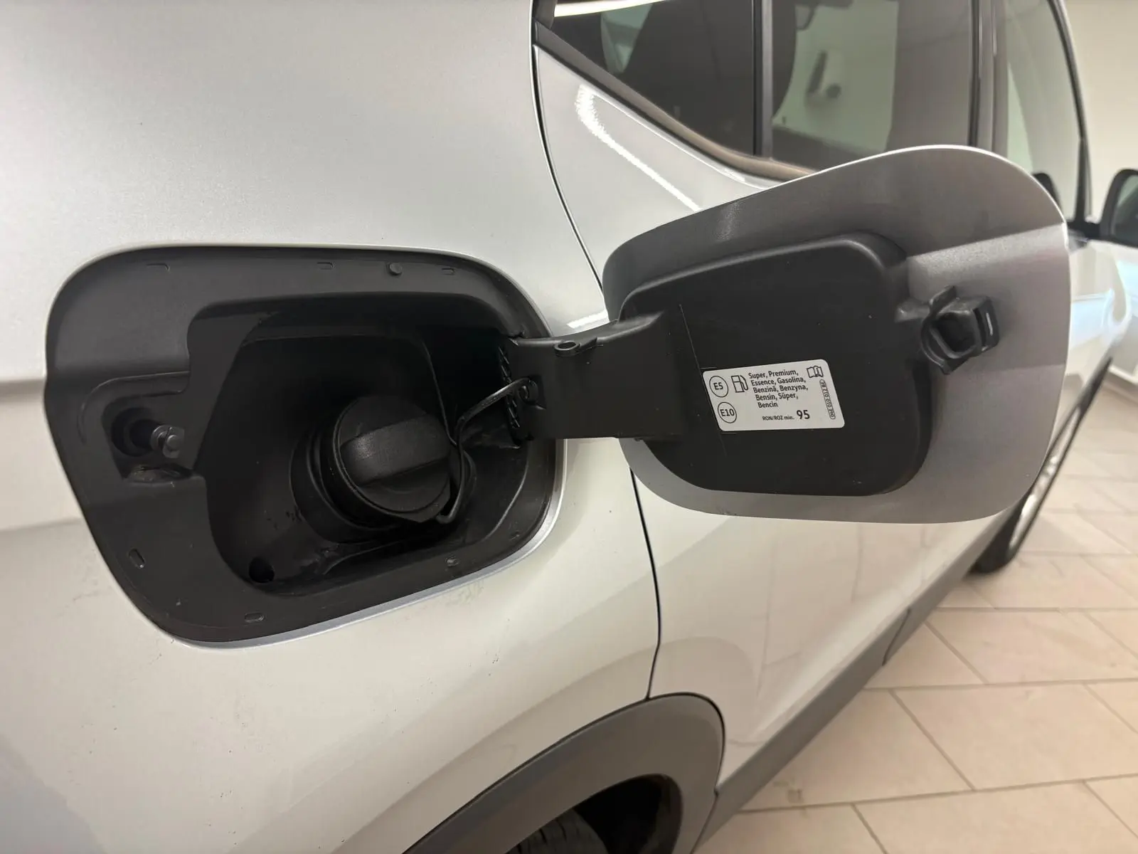 Vue rapprochée de la trappe à carburant ouverte côté gauche d’un Volkswagen T-Cross 2024 couleur reflet d’argent.
