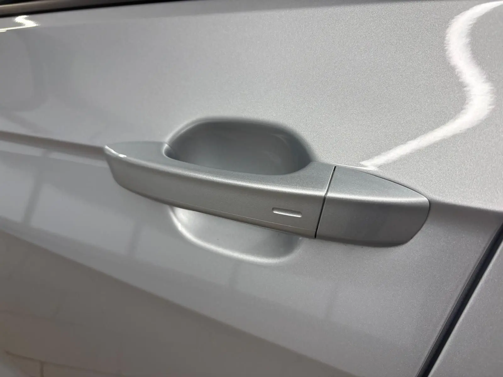 Poignée de porte côté gauche en reflet d'argent sur Volkswagen T-Cross 2024, finition VW Edition.