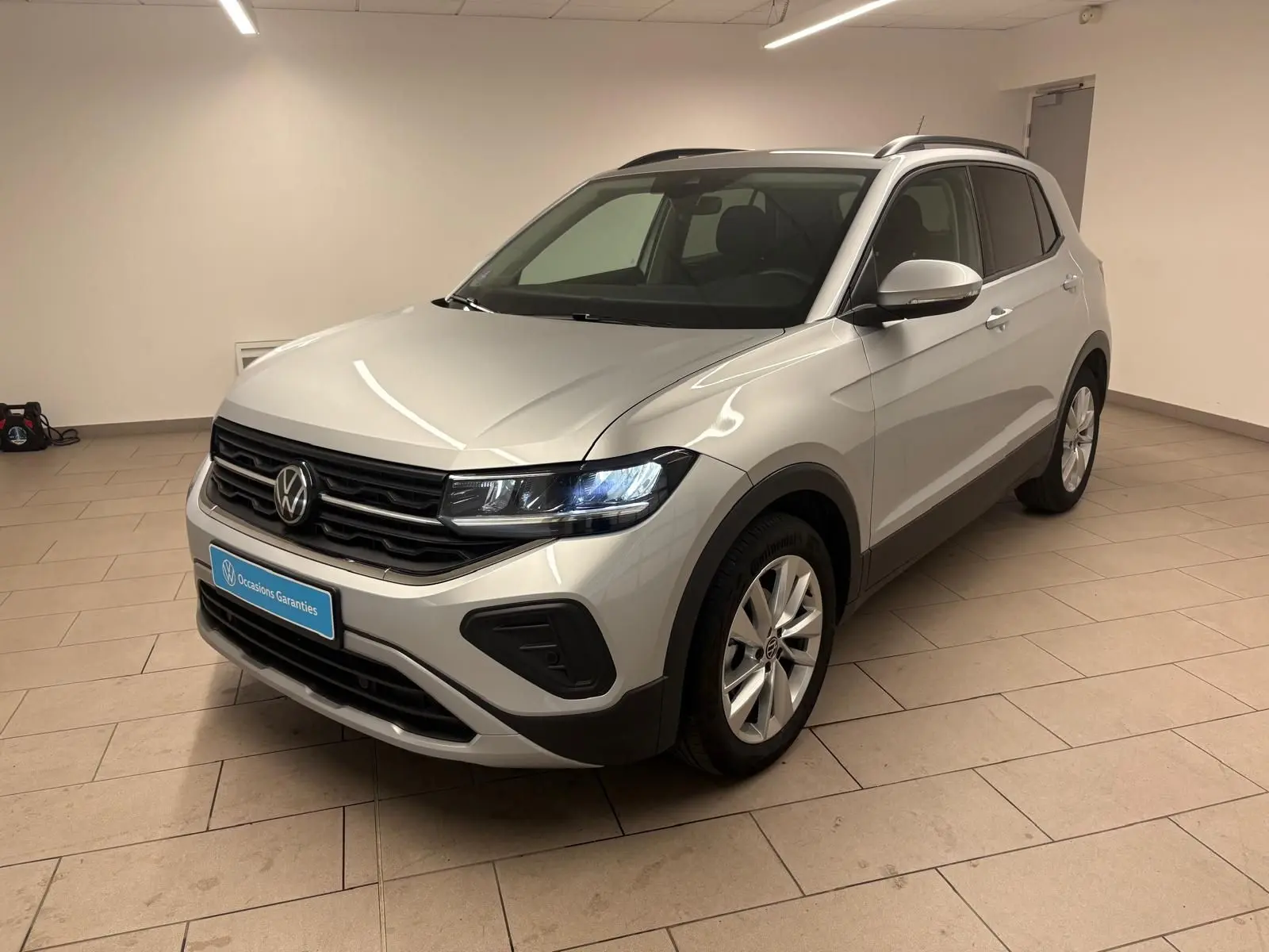 Volkswagen T-Cross 2024 reflet d'argent en 3/4 avant droit, avec jantes alliage et calandre noire.