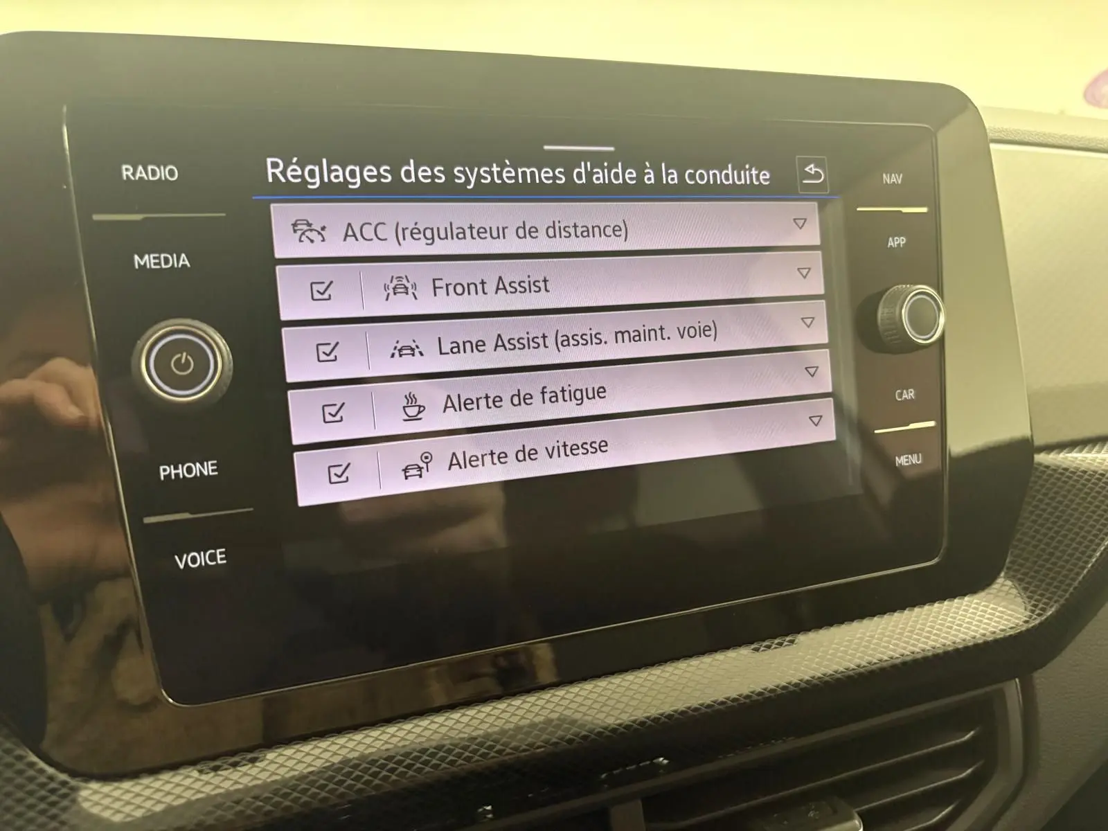 Écran tactile central du Volkswagen T-Cross 2024 affichant les réglages d'aide à la conduite en intérieur.