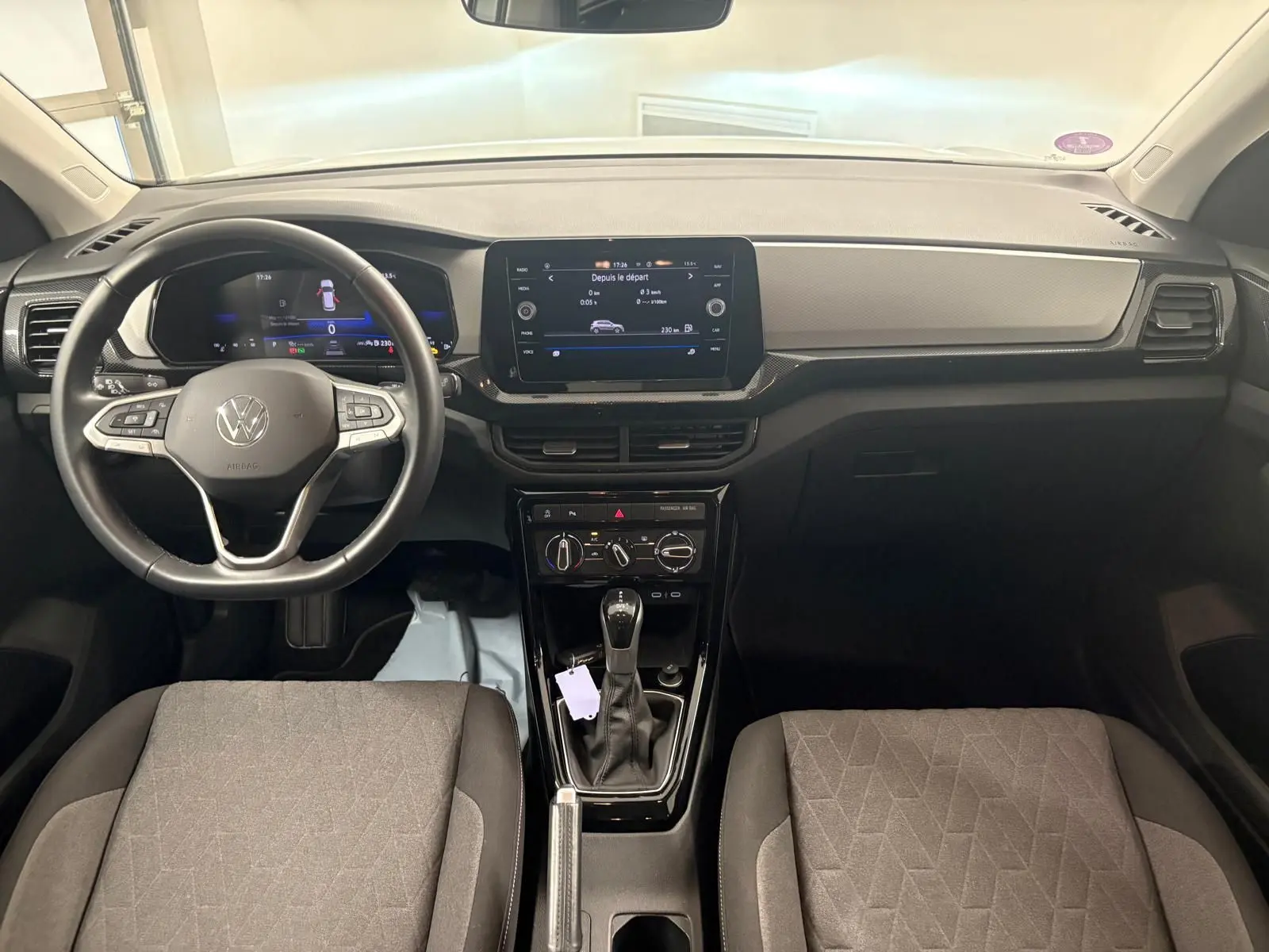 Vue intérieure avant du Volkswagen T-Cross 2024, tableau de bord noir avec écran tactile central et volant multifonction cuir.