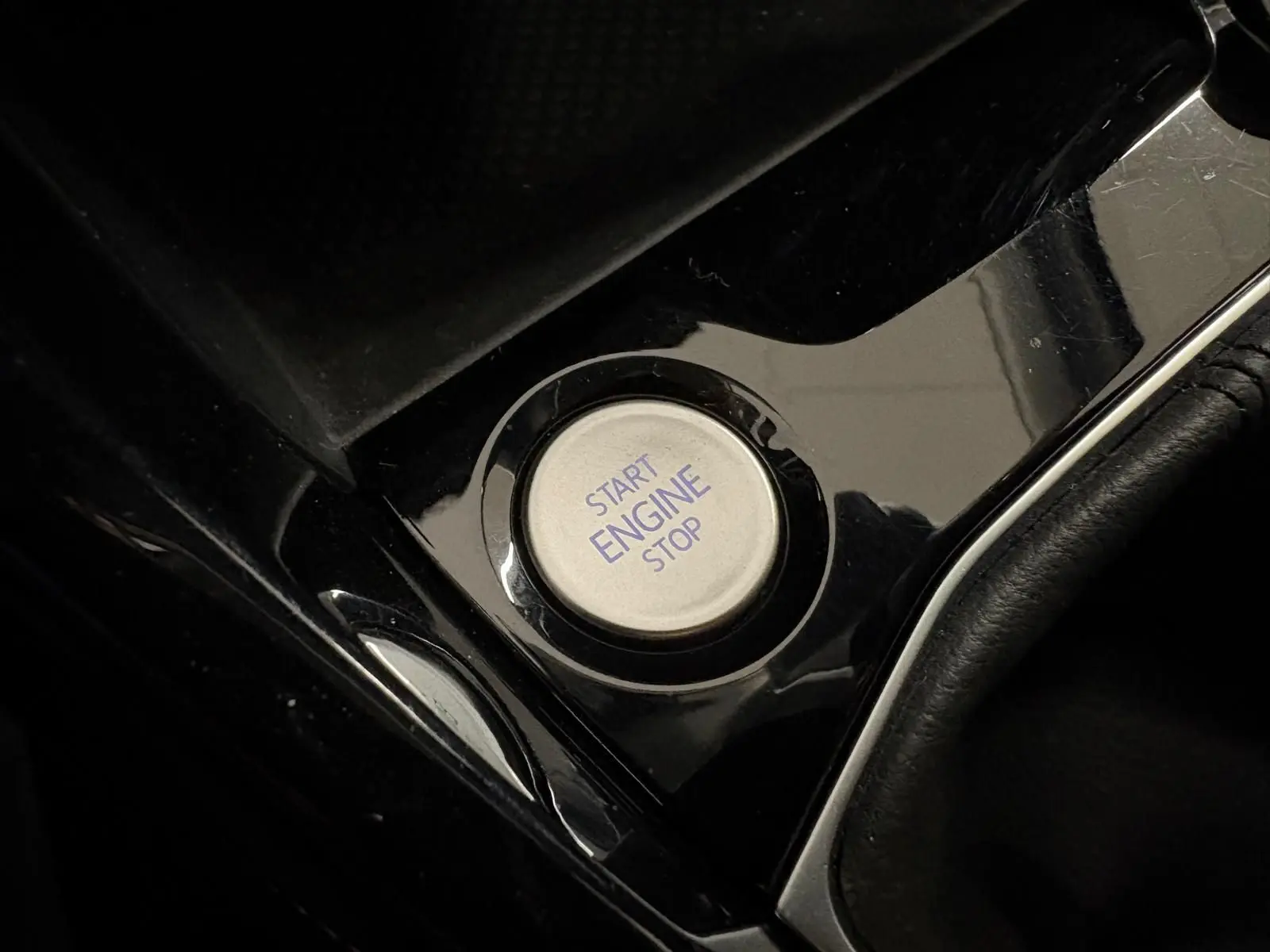 Bouton start/stop moteur argenté sur console noire brillante du Volkswagen T-Cross 2024 finition VW Edition.