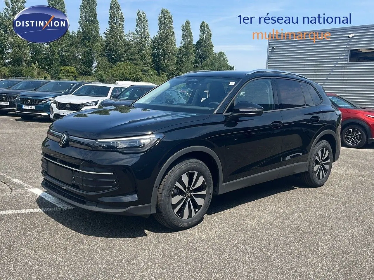 Volkswagen Tiguan noir Grenadilla 3/4 avant droit, roues alliage et calandre épurée sous un ciel bleu.