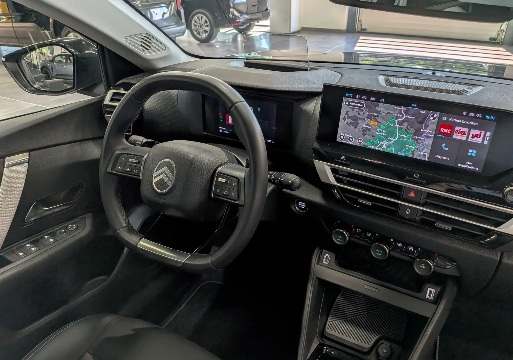 Vue intérieure côté conducteur du Citroën C4 hybride 2025, volant cuir noir et écran tactile avec navigation affichée.