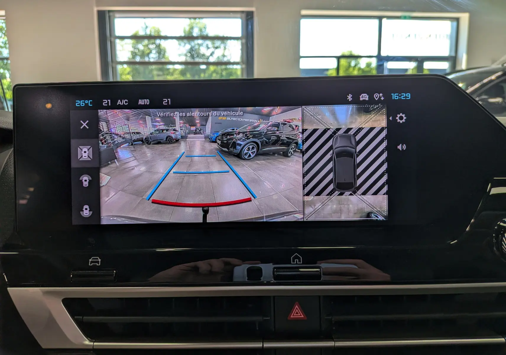 Écran multimédia de la Citroën C4 Hybride 2025 montrant la caméra de recul avec vue arrière et top-down en intérieur showroom.