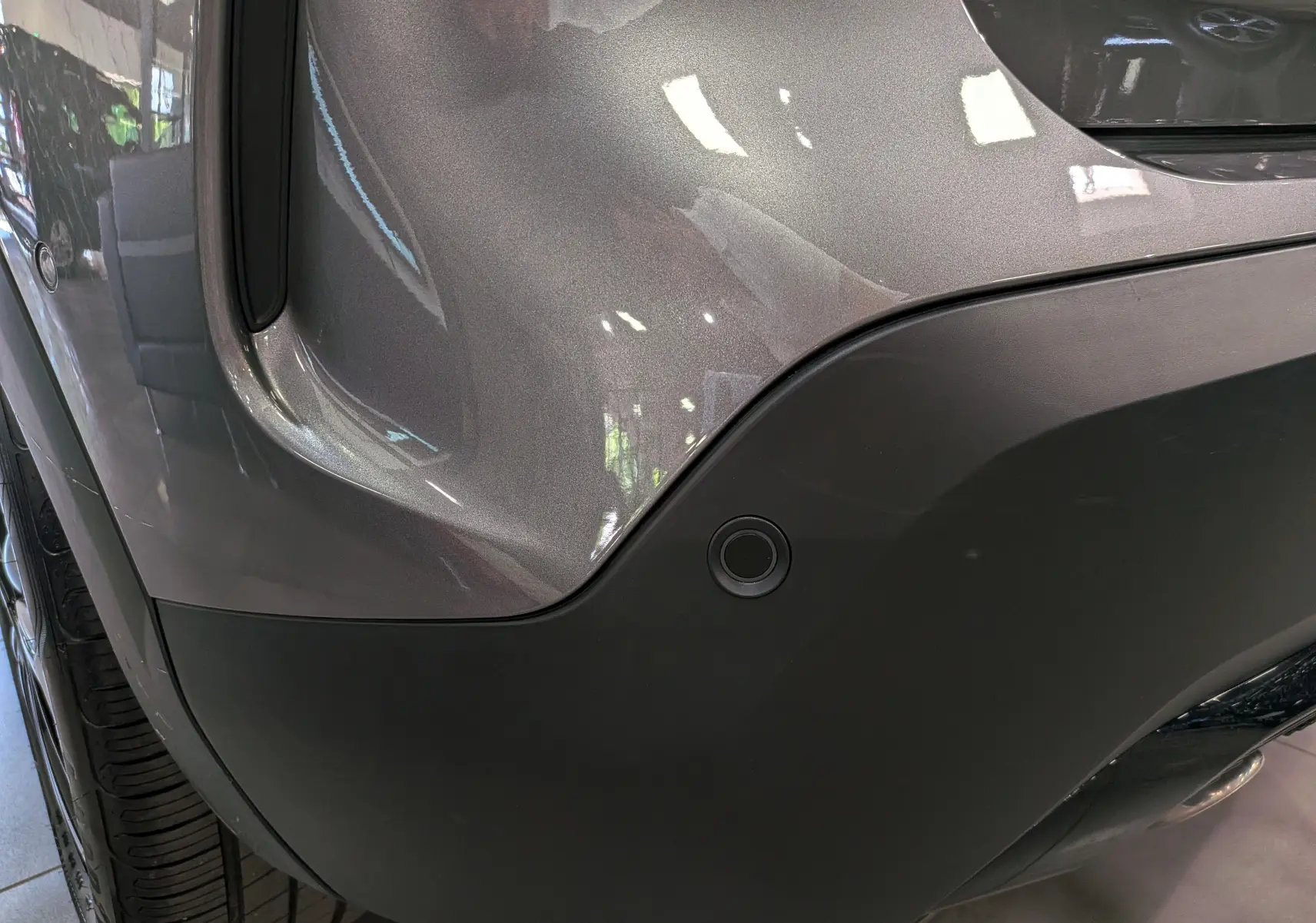 Gros plan sur l'angle arrière droit gris Mercury du Citroën C4 hybride, mettant en valeur le capteur de stationnement intégré.