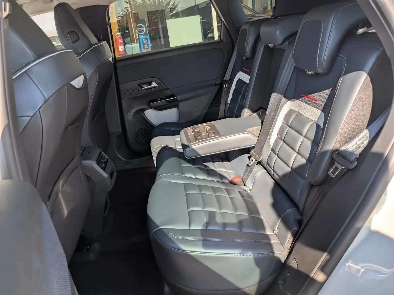 Vue intérieure côté droit des sièges arrière en cuir noir avec accoudoir central déplié du Citroën C5 Aircross blanc.