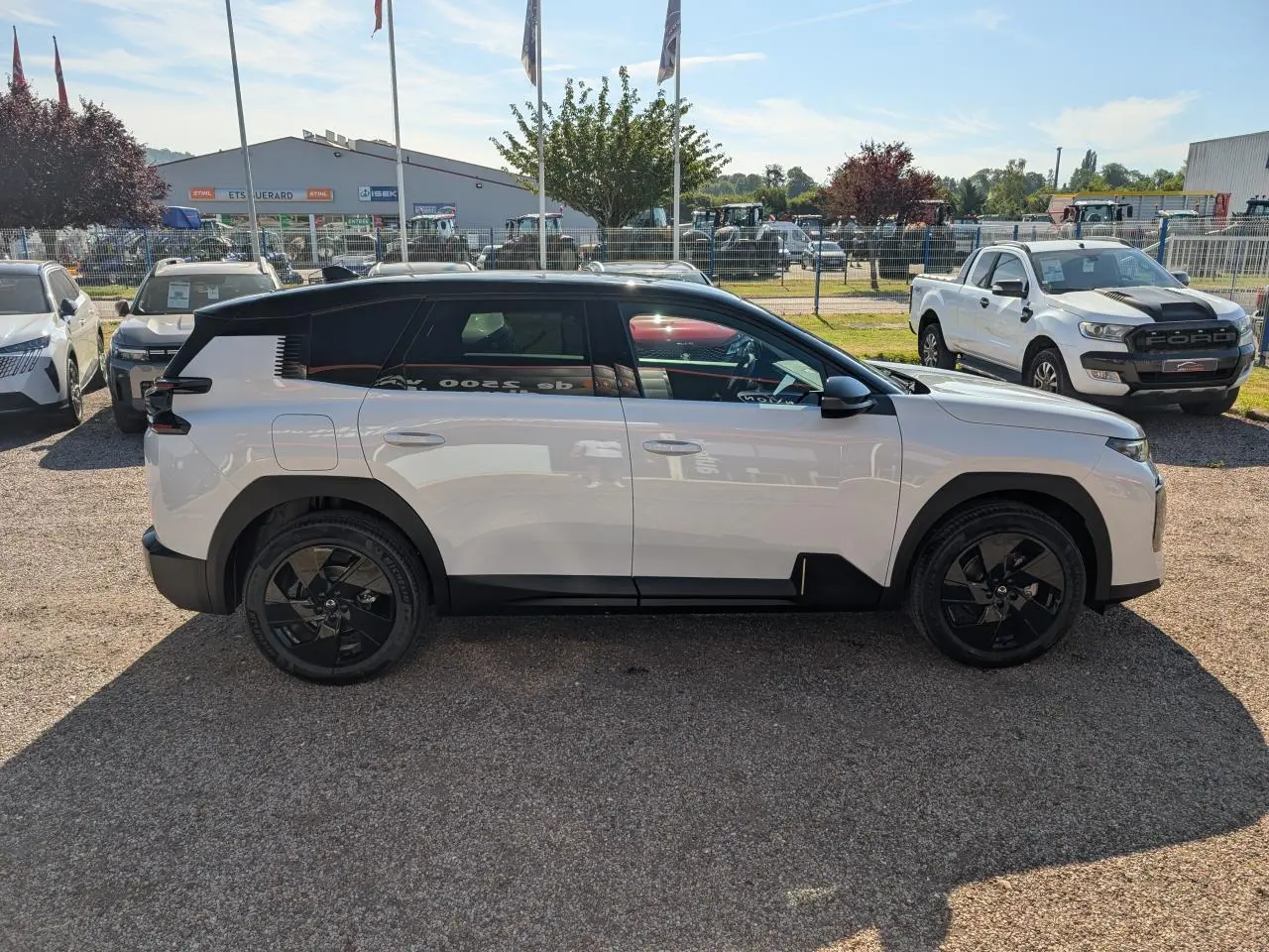 Vue de profil côté gauche d'un Citroën C5 Aircross blanc avec toit noir et jantes noires sur parking extérieur.