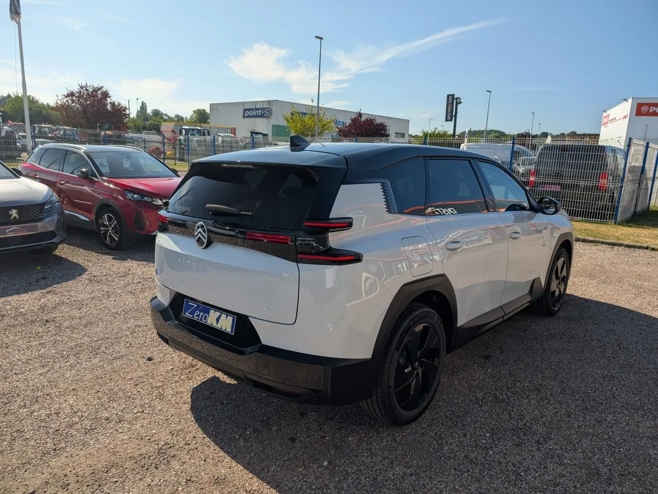 Vue 3/4 arrière droite du Citroën C5 Aircross blanc avec toit noir et jantes alliage noires sur parking.
