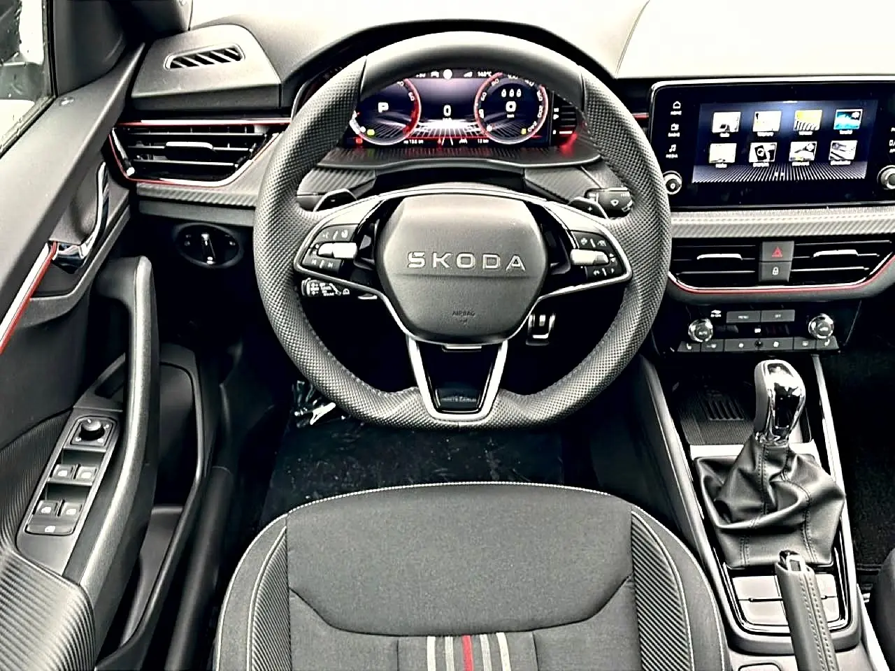 Vue intérieure centrée sur le volant sport et tableau de bord numérique du Skoda Kamiq Monte Carlo, finition noire avec inserts rouges.