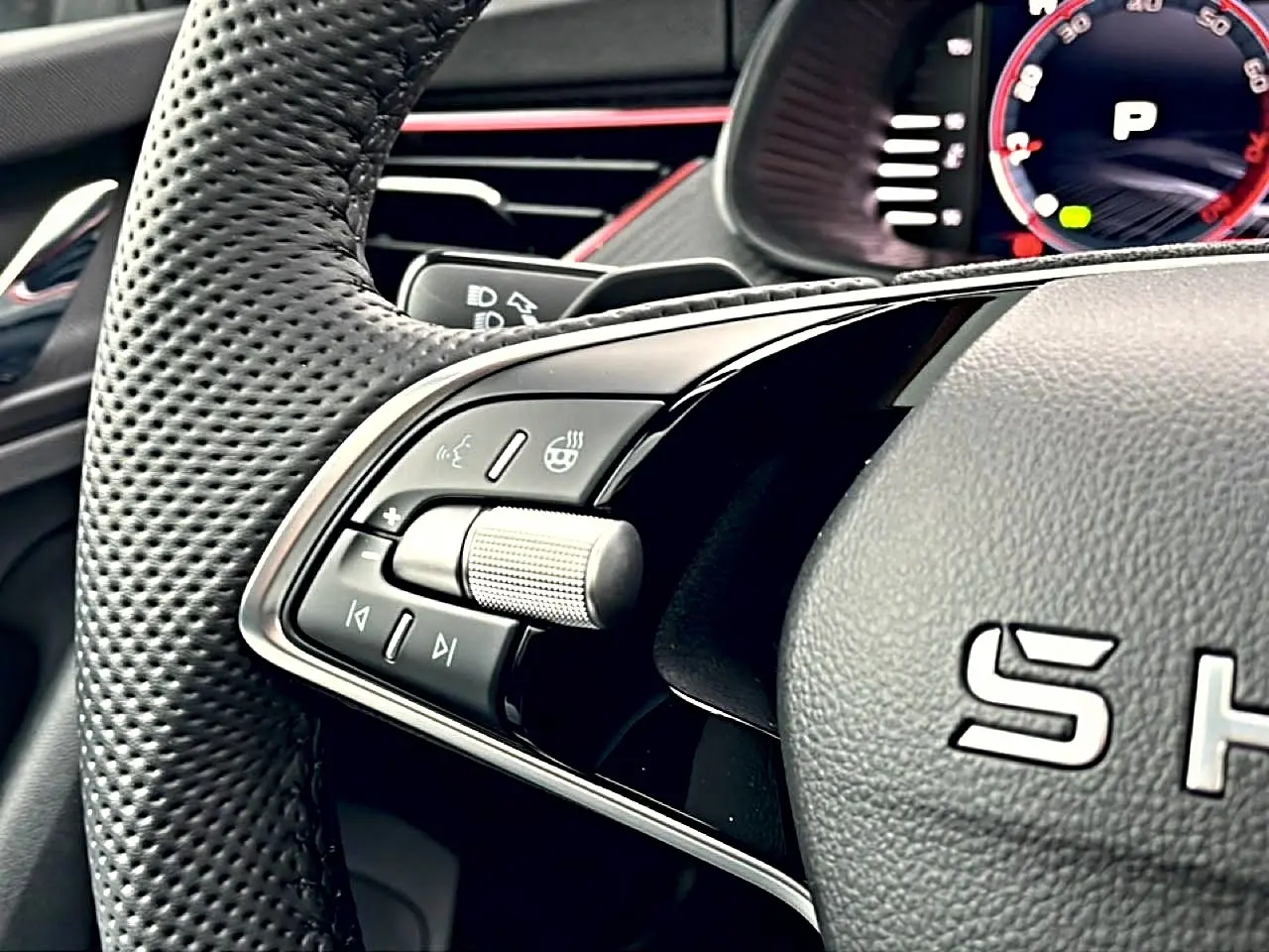 Gros plan sur les commandes gauche du volant cuir perforé du Skoda Kamiq blanc nacré, avec molette et boutons multifonctions.