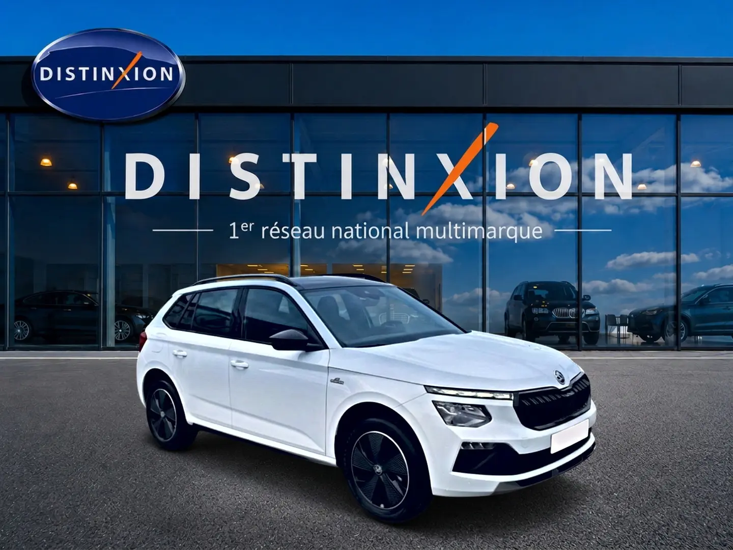 Skoda Kamiq blanc nacré en 3/4 avant droit, avec toit panoramique et jantes alu noires distinctives.
