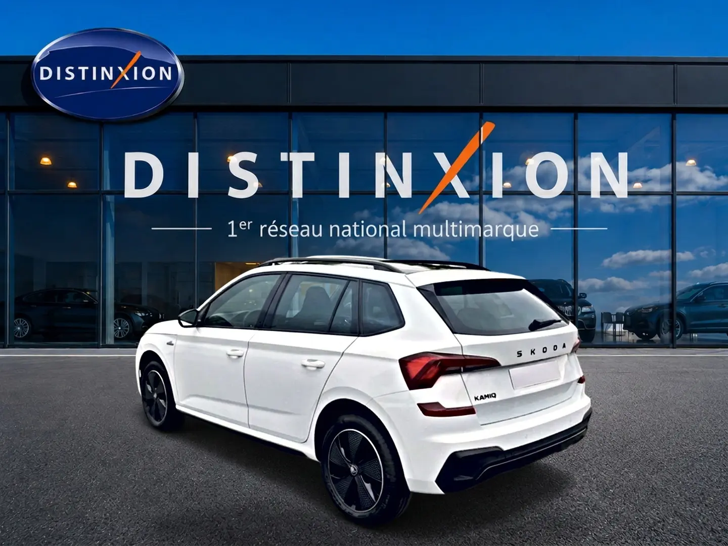 Vue 3/4 arrière droite d'un Skoda Kamiq blanc nacré avec jantes noires devant un showroom Distinxion.