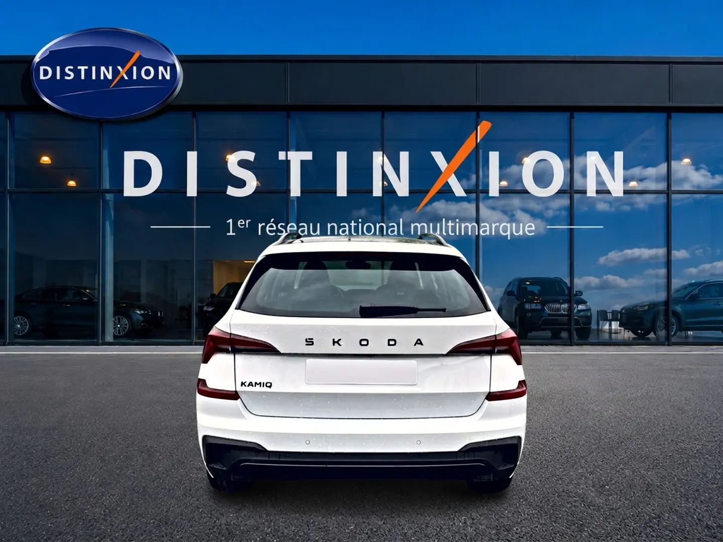 Vue arrière d'un Skoda Kamiq blanc nacré garé devant une vitrine avec logo Distinxion.