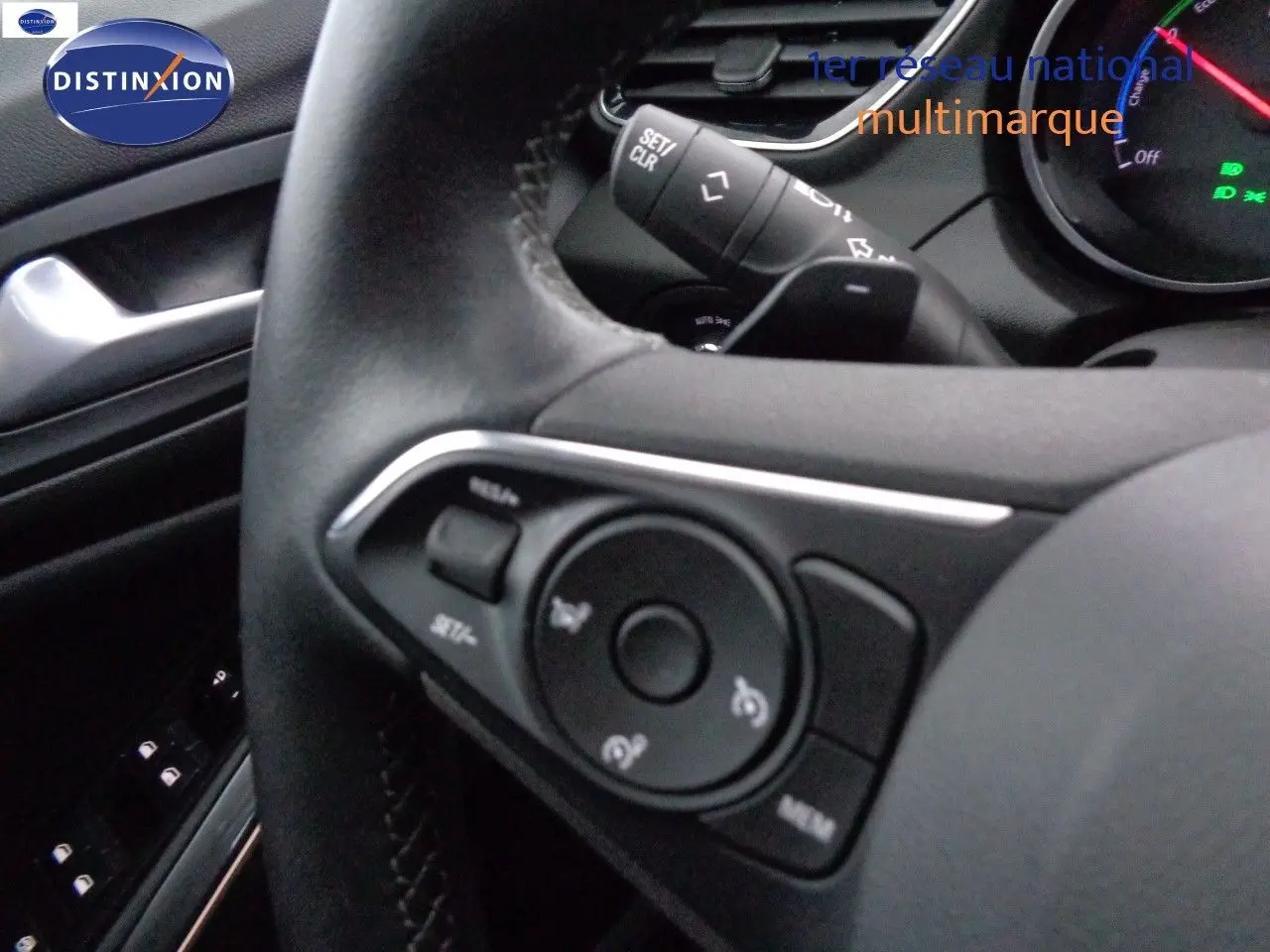 Gros plan sur le volant noir de l'Opel Grandland X hybride, montrant les commandes intégrées et le tableau de bord partiel.