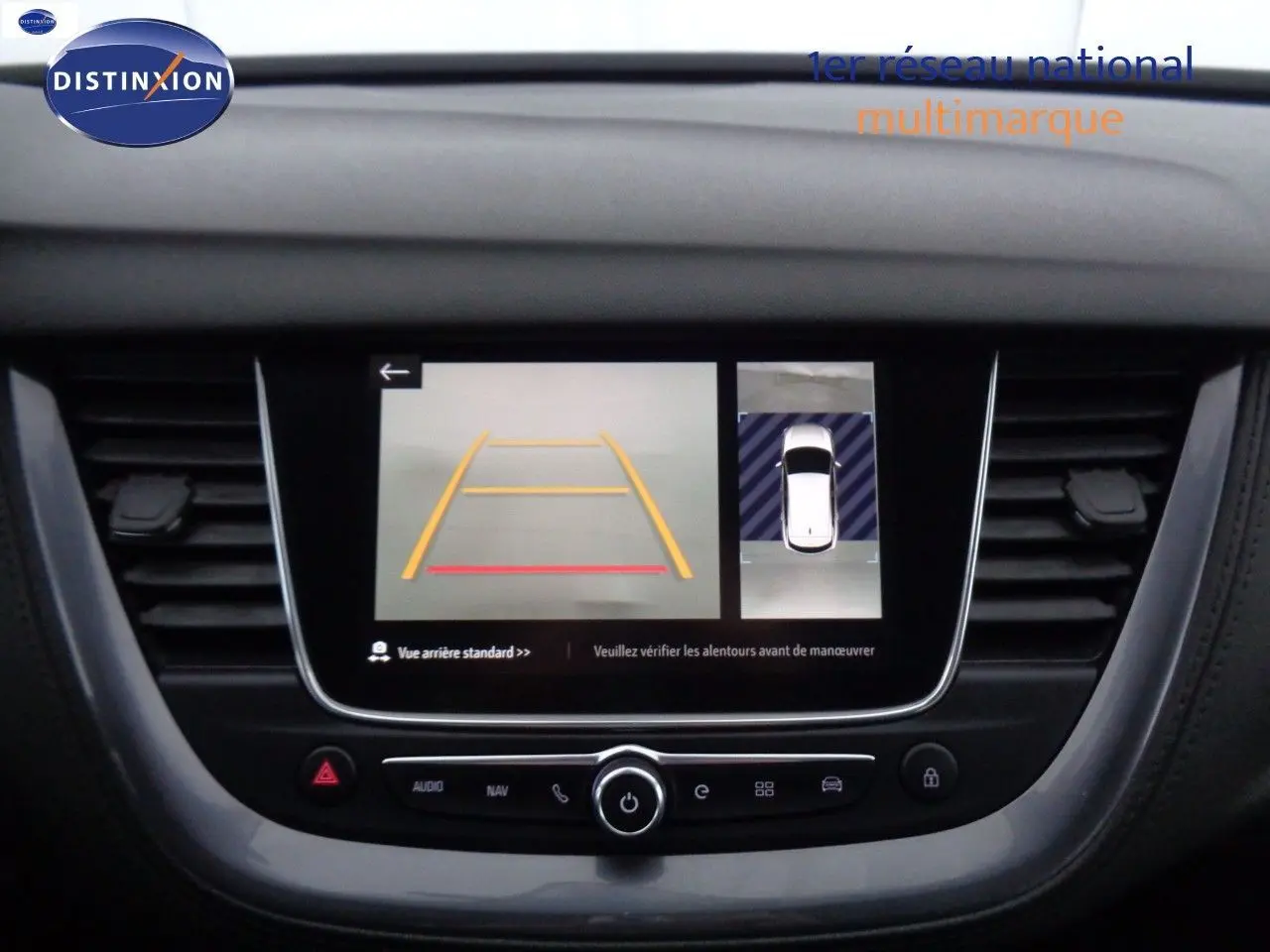 Écran central de l’Opel Grandland X blanc nacré montrant l’affichage caméra de recul et vue aérienne du véhicule.