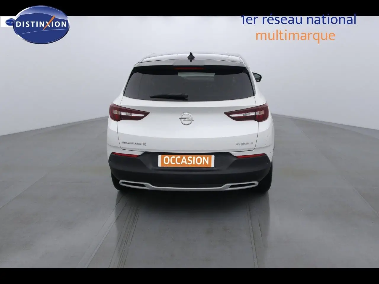 Vue arrière d'un Opel Grandland X blanc nacré hybride rechargeable avec logo et feux arrière distinctifs visibles.