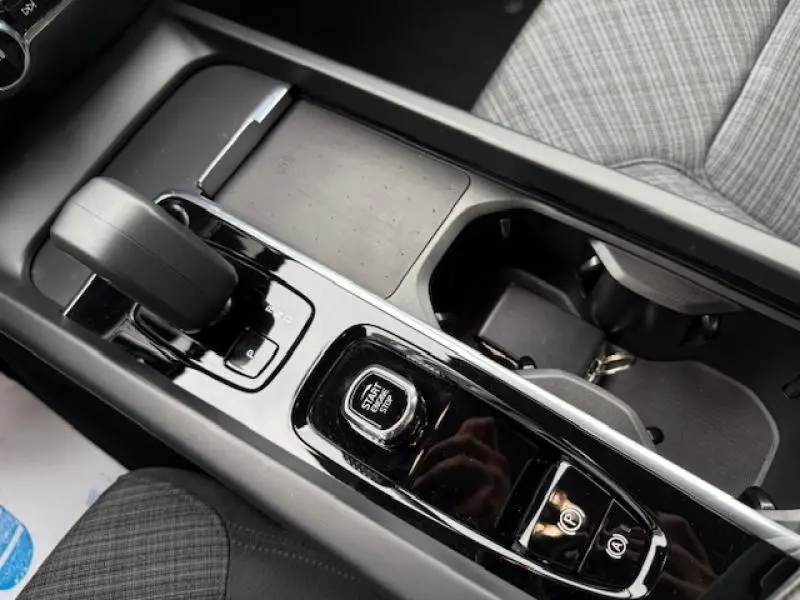 Vue rapprochée de la console centrale de la Volvo S60 rouge, mettant en valeur le levier de vitesse et le bouton start/stop.