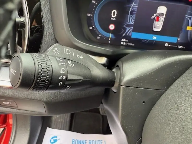 Gros plan sur la commande des phares et clignotants à gauche du volant d'une Volvo S60 2024 rouge Fusion Métallisé.