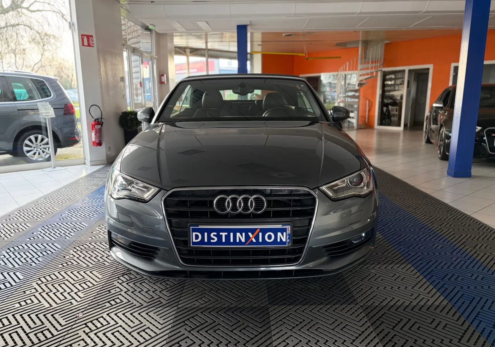 Vue frontale d'une Audi A3 Cabriolet gris métallisé de 2014 avec calandre chromée et phares LED allumés.