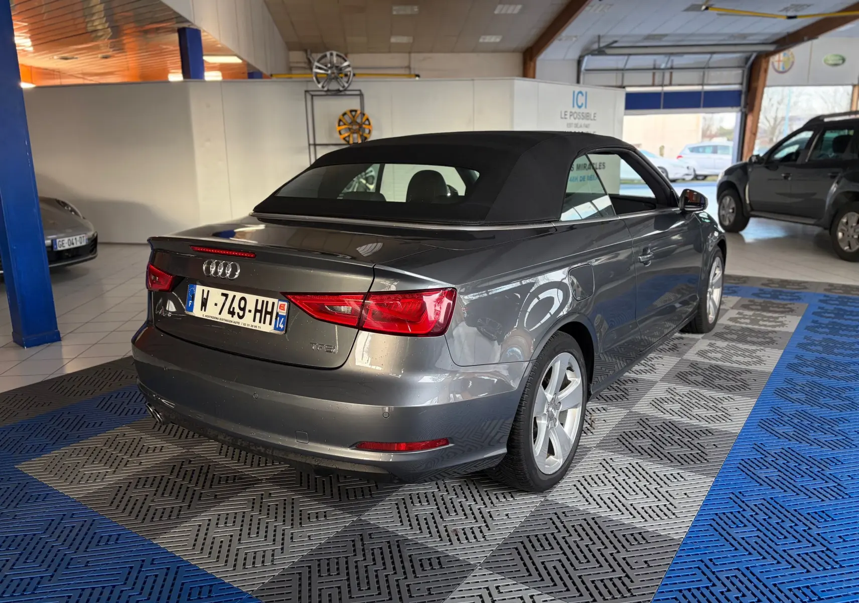 Vue intérieure côté conducteur de l'Audi A3 Cabriolet 2014, volant cuir, tableau de bord gris et levier de vitesse manuel.