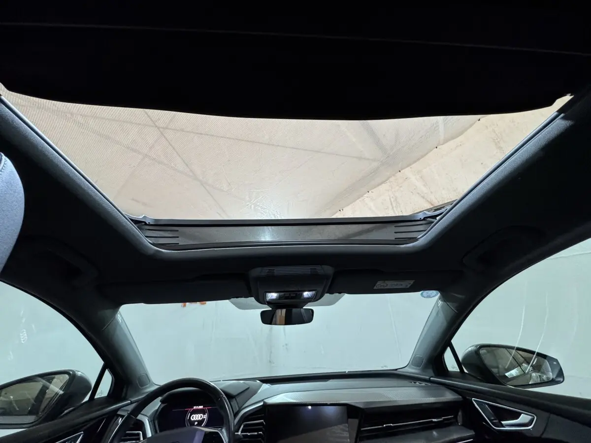 Vue intérieure avant du toit ouvrant panoramique et tableau de bord noir de l’Audi Q4 E-TRON Design Luxe 2022