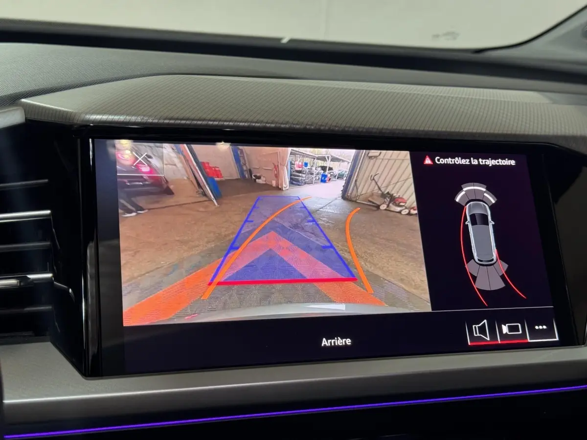 Écran tactile central de l’Audi Q4 E-TRON gris foncé montrant la caméra de recul avec guidage et alertes de trajectoire.