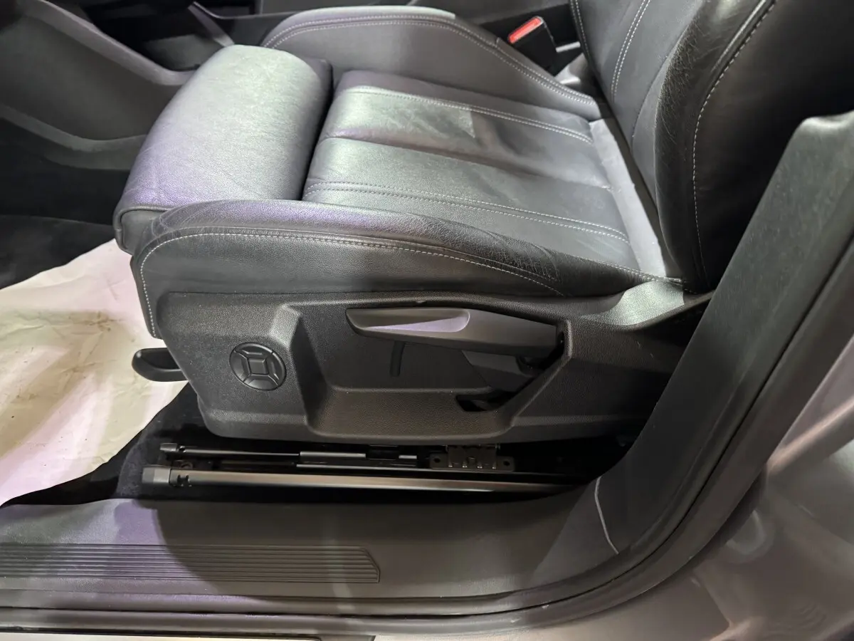 Gros plan sur le siège avant gauche en cuir noir de l'Audi Q4 E-TRON gris foncé, montrant les commandes manuelles.