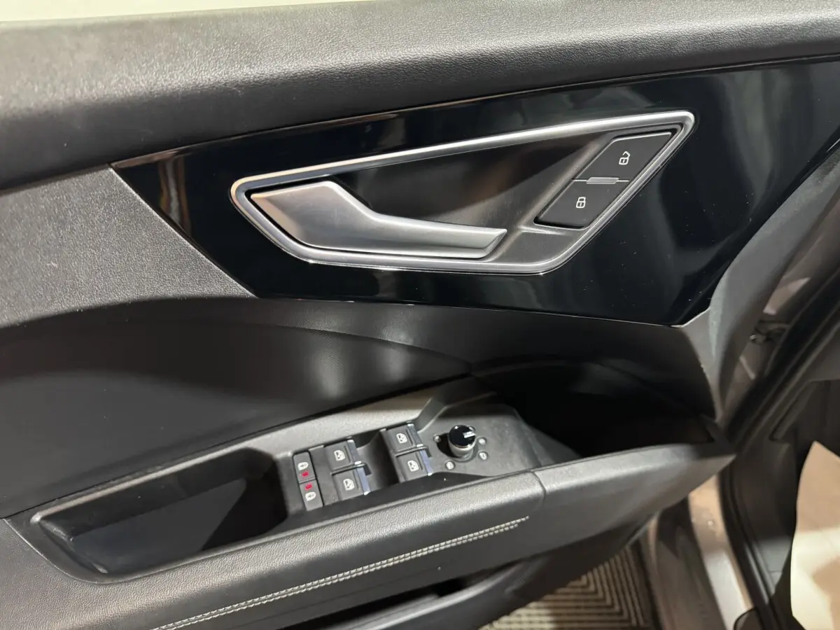 Gros plan sur la porte côté conducteur de l'Audi Q4 E-TRON gris foncé, avec commandes électriques et poignée argentée.