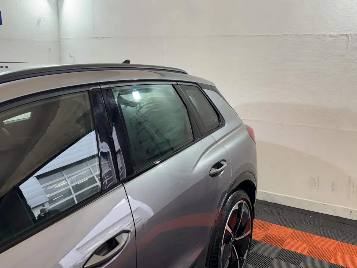 Vue côté gauche arrière d'un Audi Q4 E-TRON gris foncé avec jante noire et toit ouvrant visible