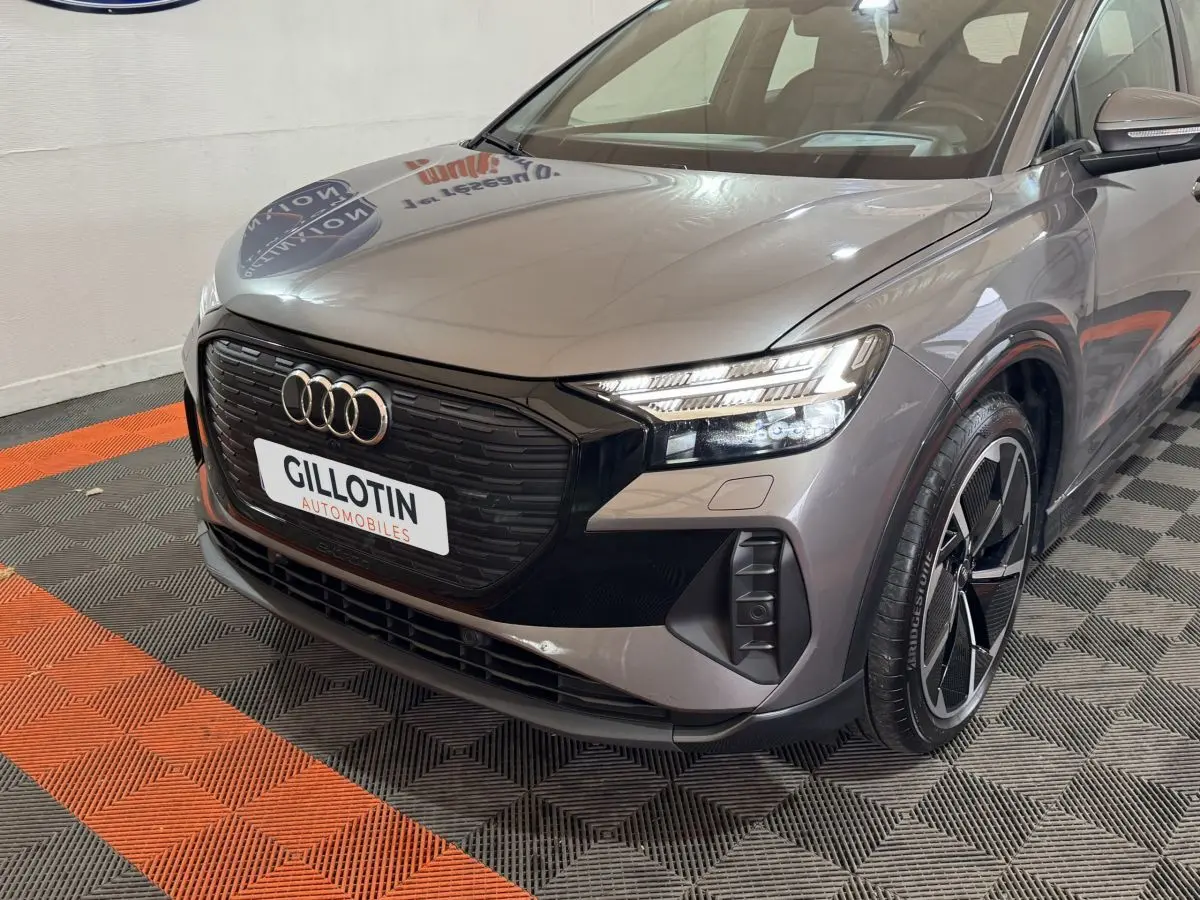 Audi Q4 E-TRON gris foncé en 3/4 avant droit, mettant en valeur sa calandre noire et ses phares LED distinctifs.