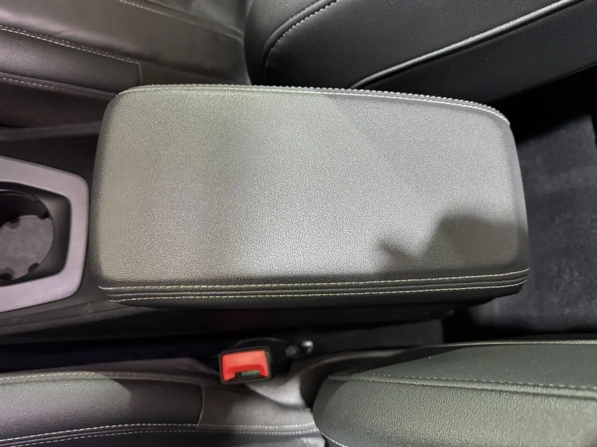 Gros plan sur l'accoudoir central en cuir noir avec surpiqûres blanches de l'Audi Q4 E-TRON gris foncé.