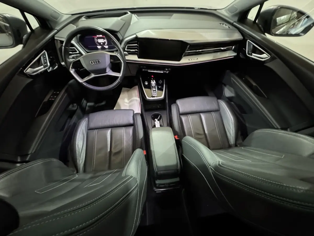 Vue intérieure de l'Audi Q4 E-TRON Design Luxe 2022, tableau de bord et sièges en cuir noir avec volant multifonctions.