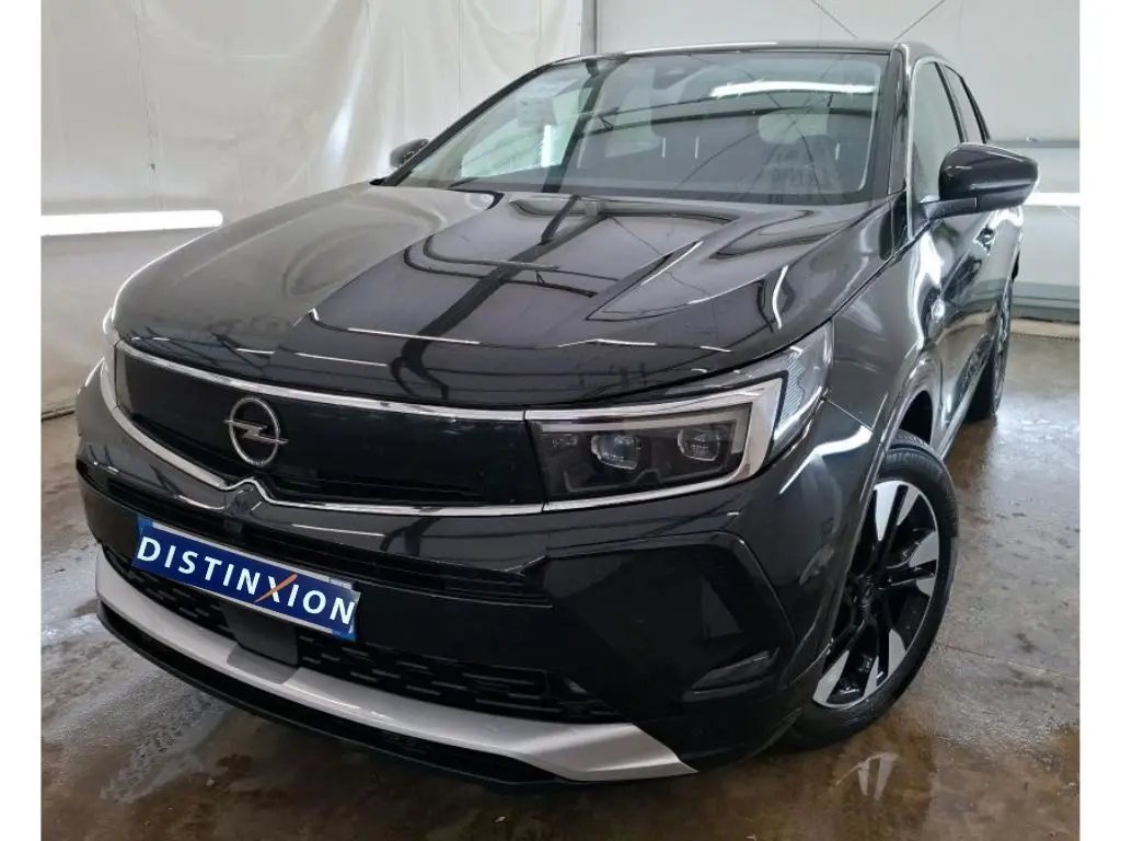 Opel Grandland noir vue 3/4 avant droit en showroom avec jantes alliage bicolores et logo Distinxion.