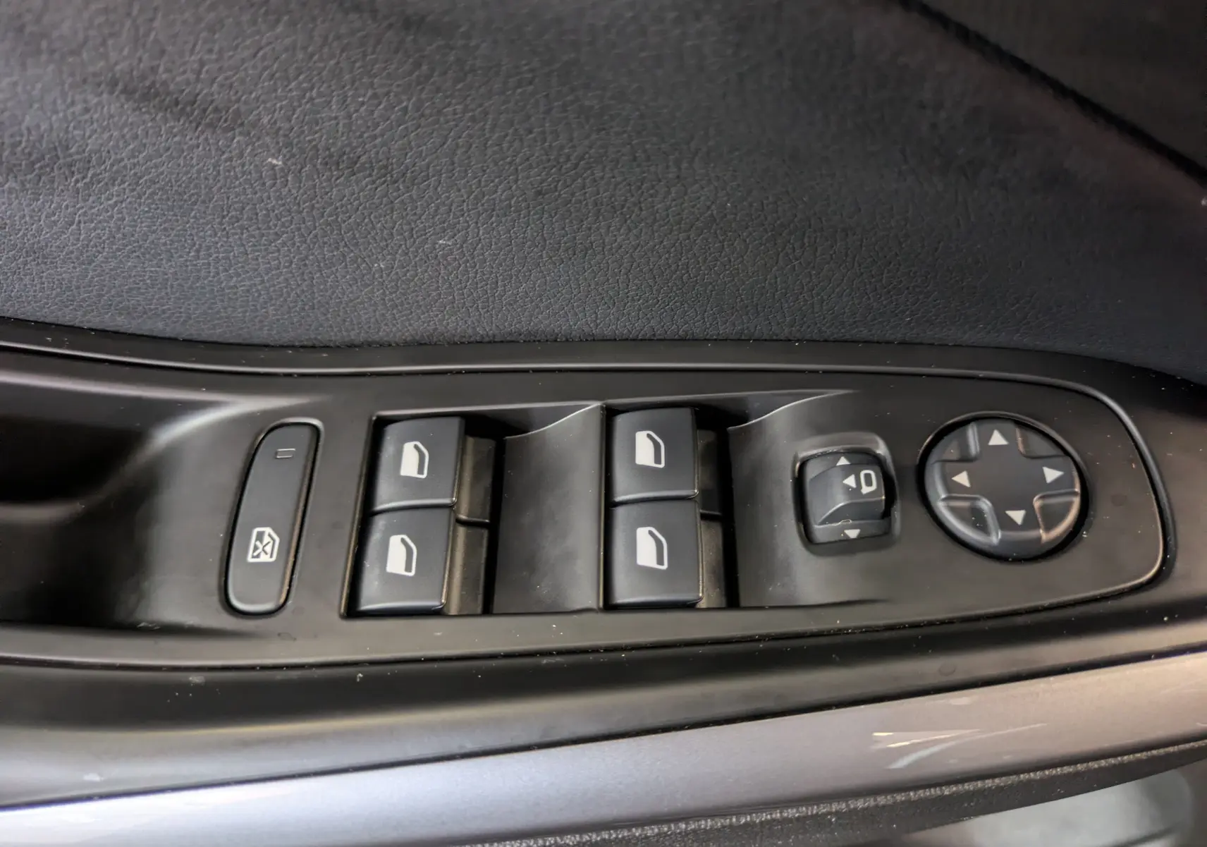 Gros plan sur les commandes de lève-vitres et réglage des rétroviseurs côté conducteur d'un Opel Grandland noir.