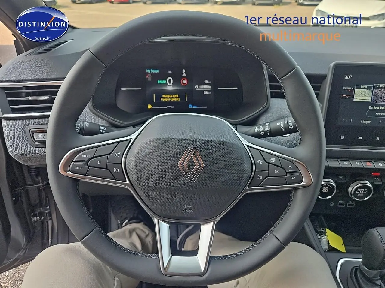 Vue intérieure centrée sur le volant noir de la Renault Clio V gris schiste avec tableau de bord numérique et écran tactile.