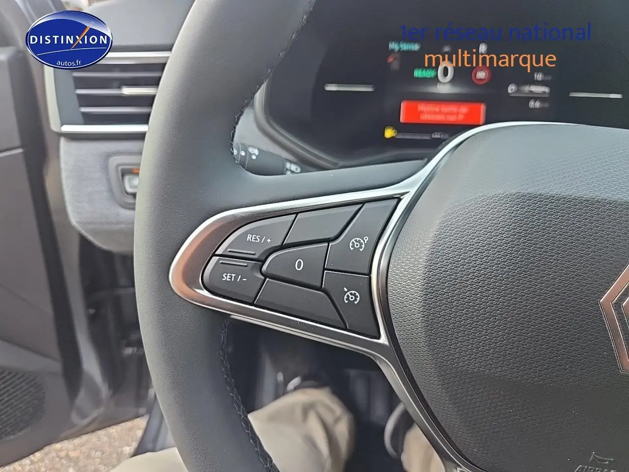 Gros plan sur le volant multifonction noir de la Renault Clio V 1.6 e-tech 145 techno, affichage numérique en arrière-plan.